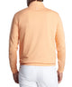 Peach-orange quarter-zip terry pullover worn with white pants, back view
